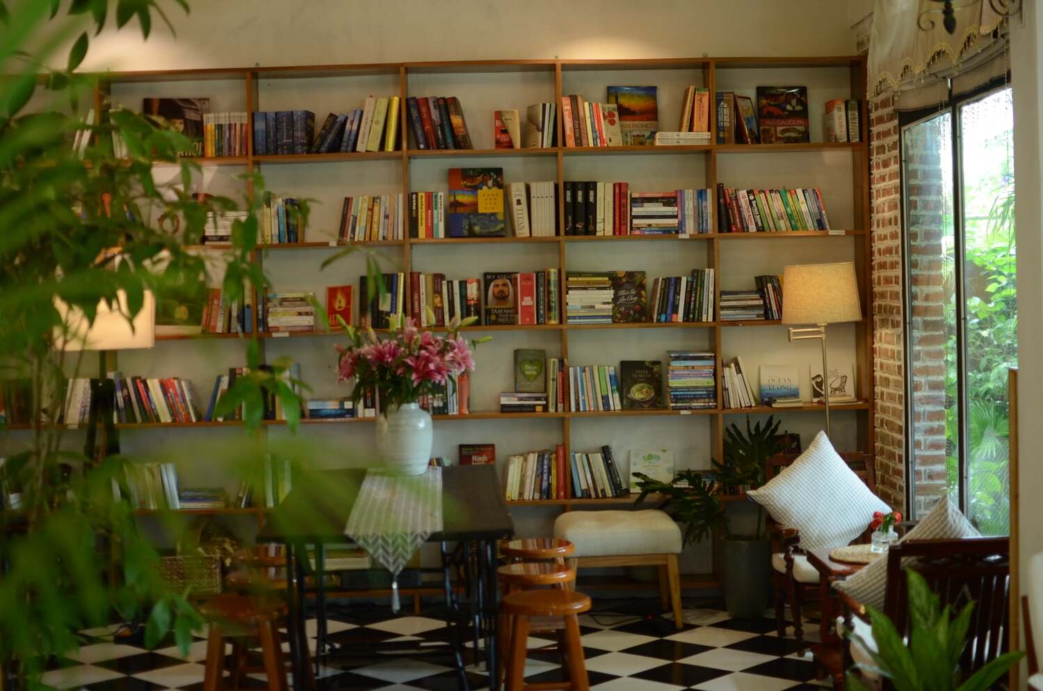 Ph&ograve;ng đọc s&aacute;ch ấm c&uacute;ng với kệ s&aacute;ch gỗ, đ&egrave;n đứng, b&igrave;nh hoa v&agrave; cửa sổ nh&igrave;n ra vườn xanh.