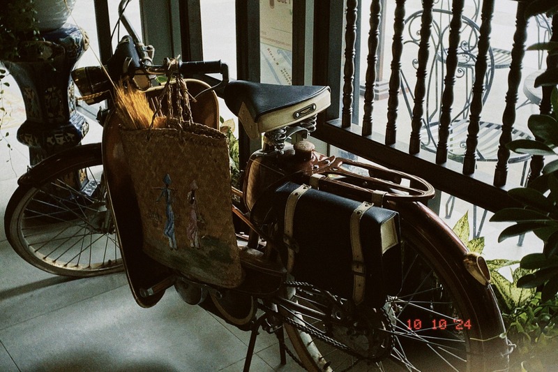 Chiếc xe đạp cổ điển với giỏ đan treo b&ecirc;n, đặt trong kh&ocirc;ng gian gần cửa sổ c&oacute; &aacute;nh s&aacute;ng tự nhi&ecirc;n.