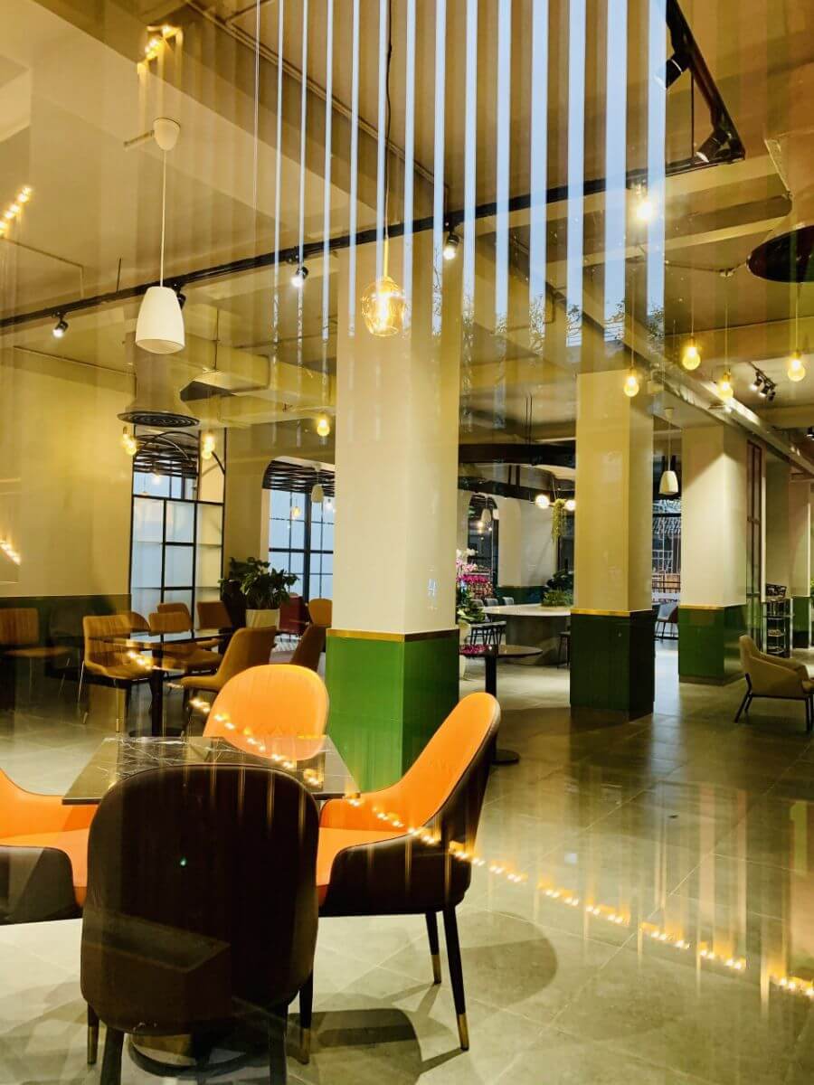 Kh&ocirc;ng gian nội thất qu&aacute;n c&agrave; ph&ecirc; với ghế m&agrave;u cam v&agrave; đ&egrave;n treo, tạo cảm gi&aacute;c ấm c&uacute;ng v&agrave; hiện đại.