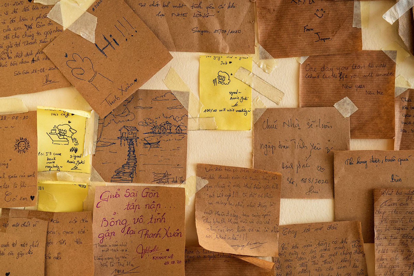 Nhiều mảnh giấy ghi ch&uacute; v&agrave; h&igrave;nh vẽ tay tr&ecirc;n tường, chứa c&aacute;c th&ocirc;ng điệp v&agrave; h&igrave;nh minh họa kh&aacute;c nhau.