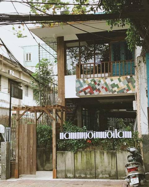 T&ograve;a nh&agrave; hai tầng với biển hiệu trước cổng, c&oacute; xe m&aacute;y đỗ b&ecirc;n ngo&agrave;i, c&acirc;y xanh bao quanh.