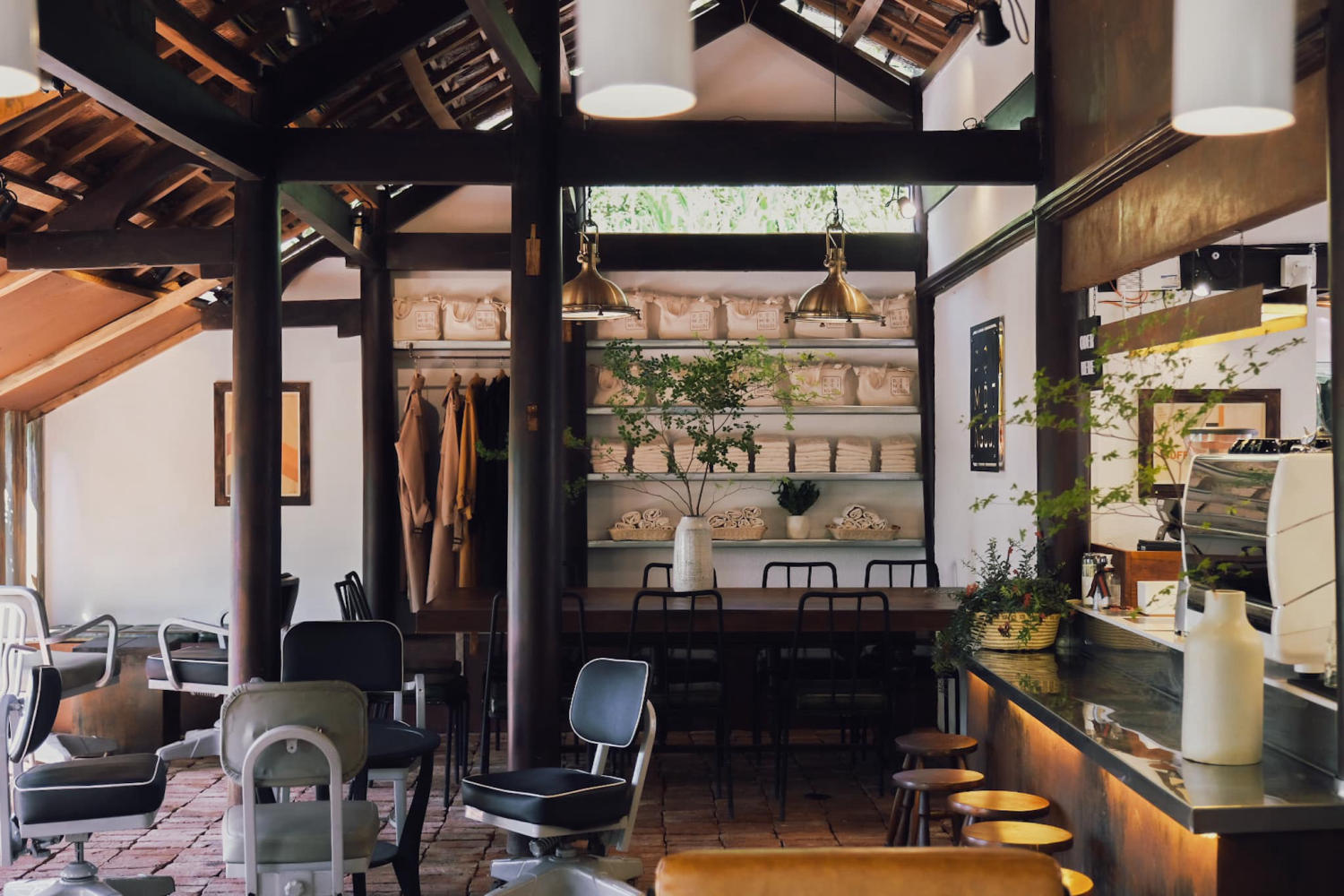 Kh&ocirc;ng gian nội thất qu&aacute;n c&agrave; ph&ecirc; với b&agrave;n ghế, c&acirc;y xanh, &aacute;nh s&aacute;ng ấm &aacute;p v&agrave; trần nh&agrave; bằng gỗ.