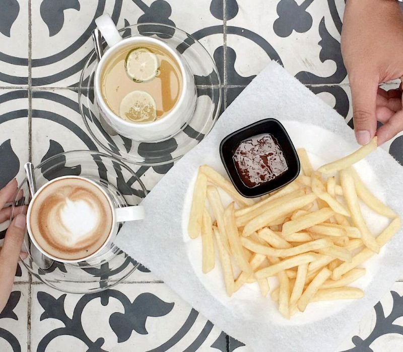 Cà phê, trà chanh và khoai tây chiên với sốt trên nền gạch hoa trang trí.