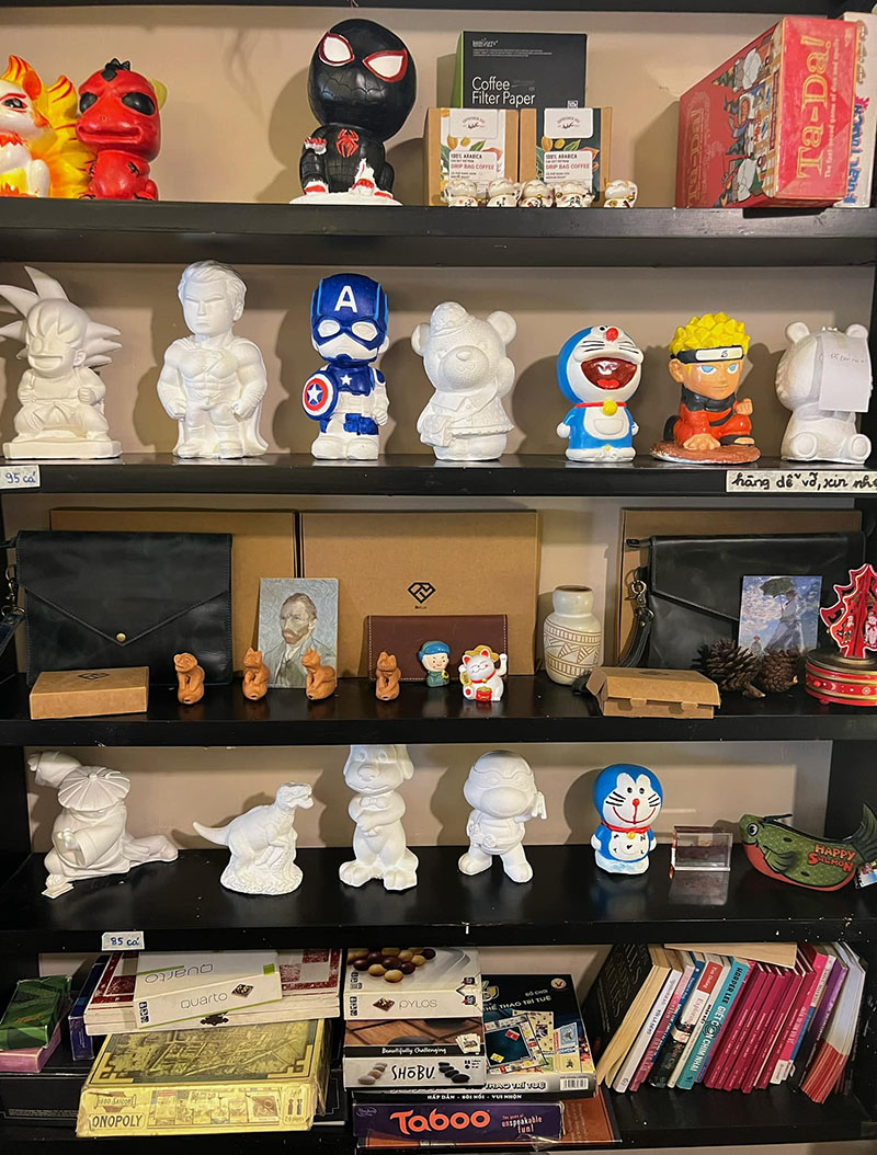 Kệ s&aacute;ch với nhiều tượng nh&acirc;n vật hoạt h&igrave;nh v&agrave; hộp tr&ograve; chơi, s&aacute;ch xếp gọn g&agrave;ng ở c&aacute;c ngăn.