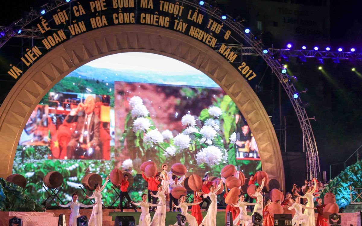 Biểu diễn nghệ thuật tại Lễ hội Cà phê Buôn Ma Thuột 2017 trên sân khấu lớn với nền hoa trắng.