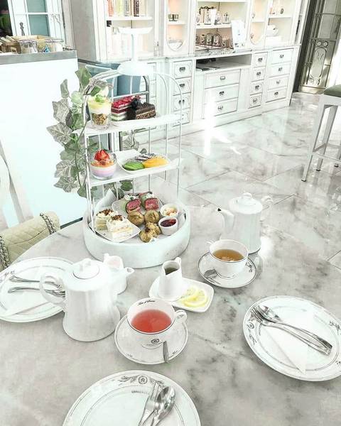 B&agrave;n tr&agrave; chiều với b&aacute;nh ngọt, tr&agrave; v&agrave; đồ sứ trắng, được b&agrave;y biện tinh tế trong kh&ocirc;ng gian nội thất sang trọng.