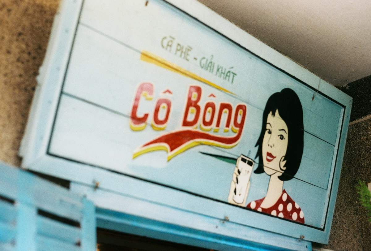 Biển hiệu quảng cáo đồ uống với hình vẽ người phụ nữ và dòng chữ "Cô Bông".