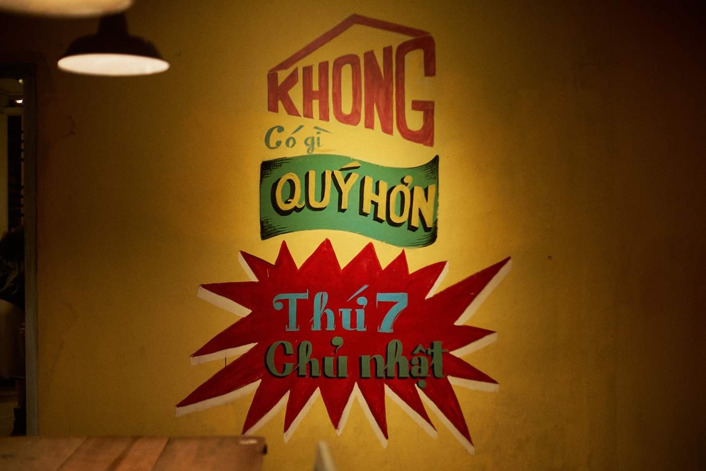 Dòng chữ trên tường với nội dung "Không có gì quý hơn Thứ 7, Chủ nhật" trên nền vàng.
