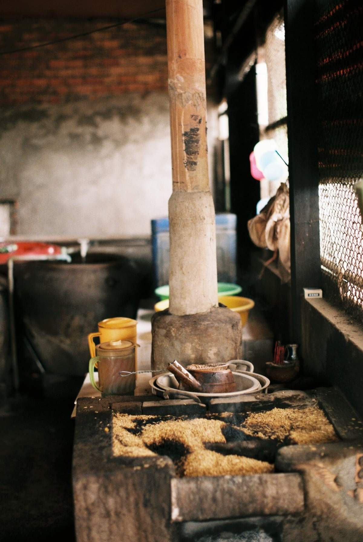 G&oacute;c bếp truyền thống với cối xay v&agrave; c&aacute;c vật dụng như nồi, cốc, b&aacute;t đĩa, v&agrave; gạo tr&ecirc;n nền bếp.