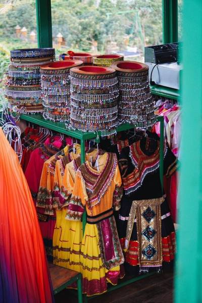 Trang phục truyền thống nhiều m&agrave;u sắc v&agrave; mũ trang tr&iacute; được trưng b&agrave;y tr&ecirc;n kệ trong một cửa h&agrave;ng.
