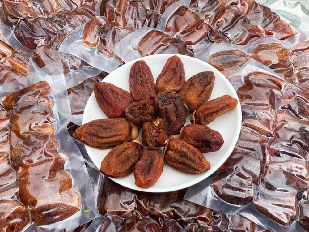 Đĩa hồng sấy kh&ocirc; được b&agrave;y tr&ecirc;n nền nhiều g&oacute;i hồng sấy đ&oacute;ng g&oacute;i ch&acirc;n kh&ocirc;ng.