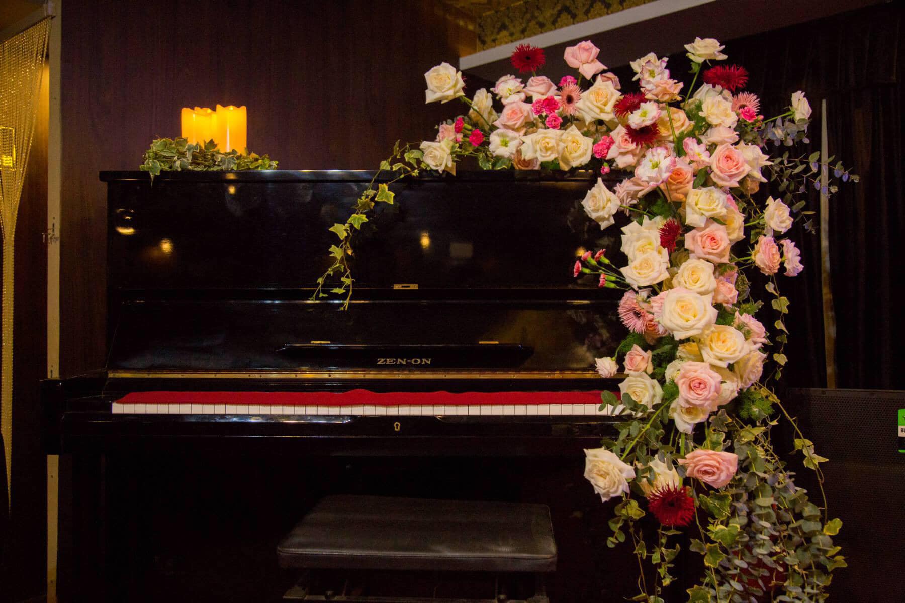 Piano đen trang tr&iacute; hoa hồng v&agrave; nến, tạo kh&ocirc;ng gian l&atilde;ng mạn v&agrave; nghệ thuật.