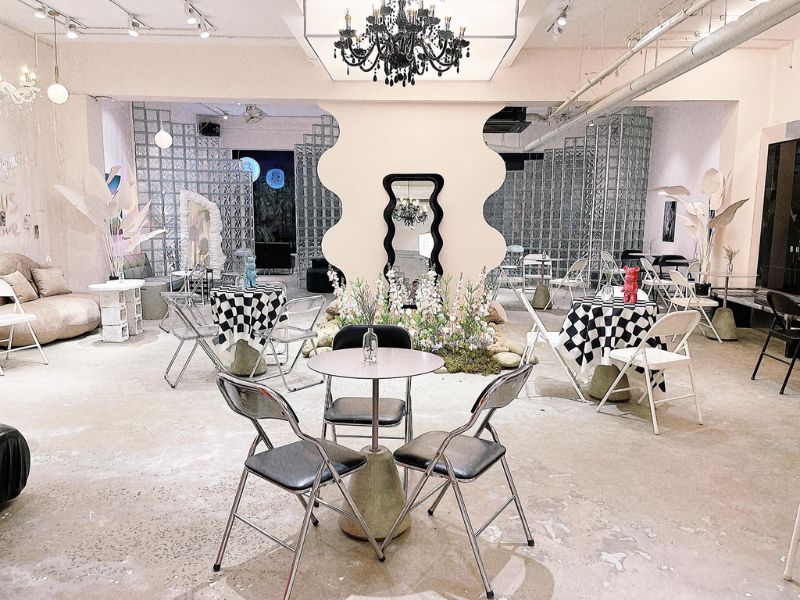 Qu&aacute;n c&agrave; ph&ecirc; với b&agrave;n ghế xếp, gương trang tr&iacute;, đ&egrave;n ch&ugrave;m v&agrave; c&acirc;y xanh tạo kh&ocirc;ng gian hiện đại v&agrave; tho&aacute;ng đ&atilde;ng.