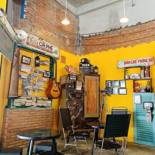 Qu&aacute;n c&agrave; ph&ecirc; với trang tr&iacute; ho&agrave;i cổ, tường gạch, đ&agrave;n guitar, s&aacute;ch, v&agrave; đồ vật trang tr&iacute; phong c&aacute;ch vintage.