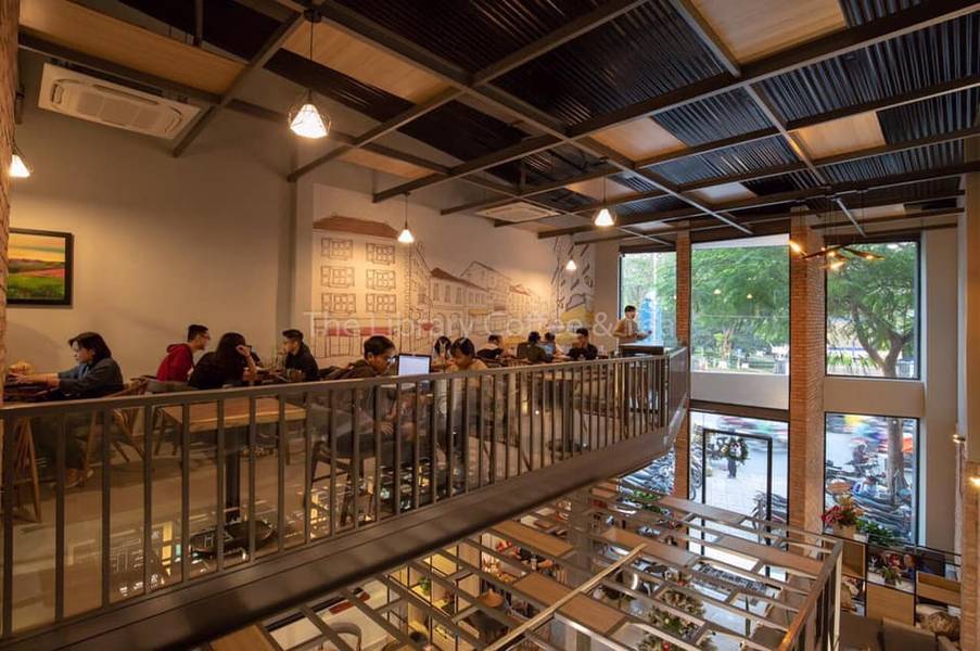 Qu&aacute;n c&agrave; ph&ecirc; với kh&ocirc;ng gian hai tầng, nhiều người ngồi l&agrave;m việc, &aacute;nh s&aacute;ng ấm &aacute;p, cửa sổ lớn nh&igrave;n ra đường phố.