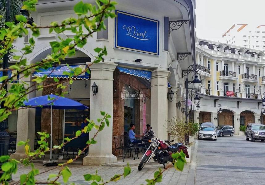 Qu&aacute;n c&agrave; ph&ecirc; với m&aacute;i hi&ecirc;n xanh, hai người ngồi tr&ograve; chuyện b&ecirc;n ngo&agrave;i, c&oacute; c&acirc;y xanh v&agrave; xe m&aacute;y ph&iacute;a trước.