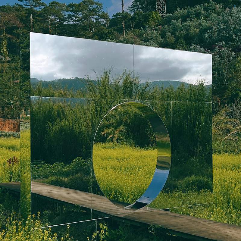 C&aacute;nh đồng hoa v&agrave;ng với tấm gương lớn phản chiếu phong cảnh xanh tươi v&agrave; bầu trời nhiều m&acirc;y.