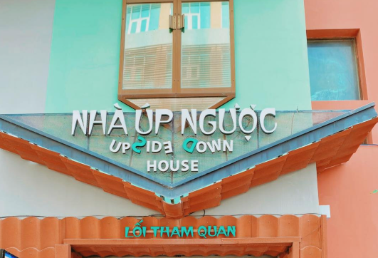 Mặt tiền của một tòa nhà với biển hiệu "Nhà Úp Ngược" và cửa sổ phía trên.