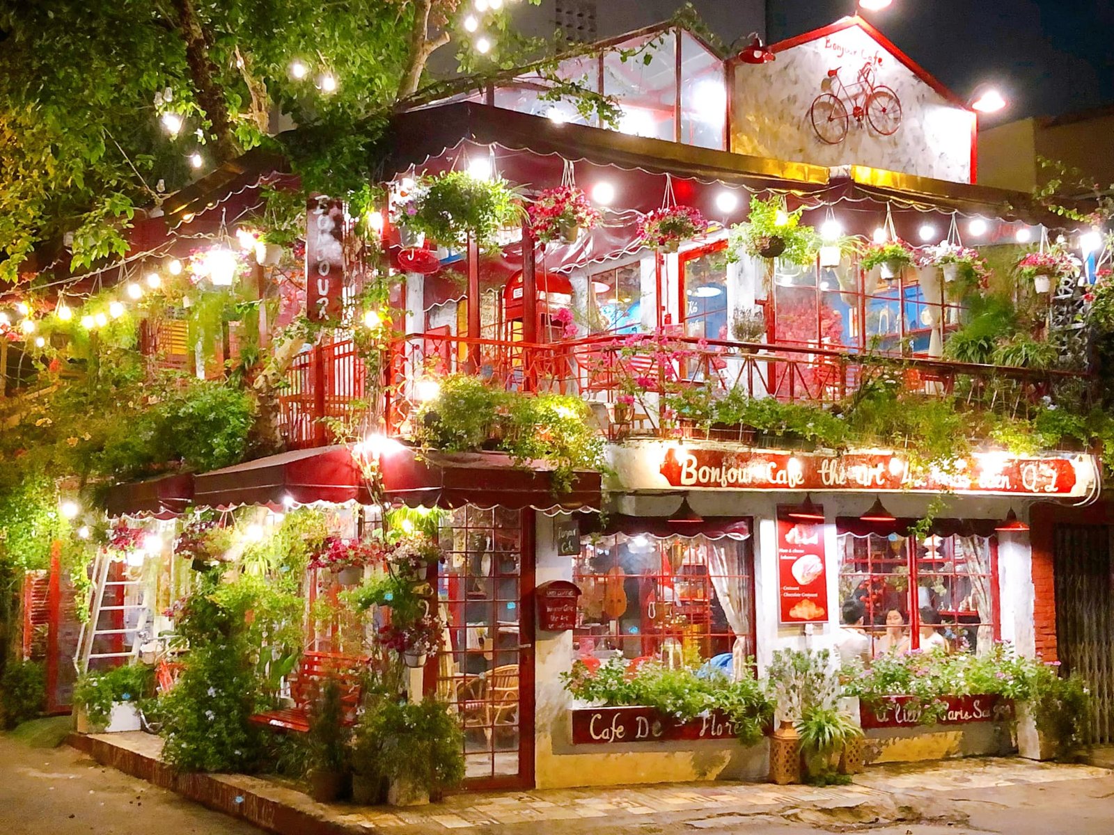 Quán cà phê phong cách châu Âu lãng mạn, trang trí đèn và cây xanh rực rỡ vào buổi tối.