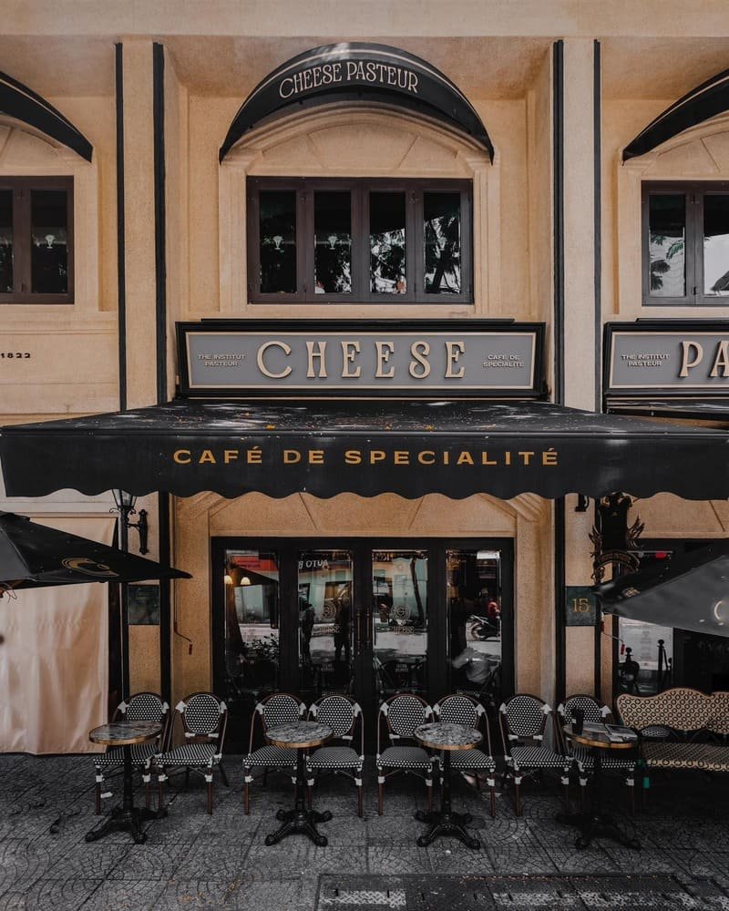 Quán cà phê kiểu Pháp với tấm biển Café de Spécialité và các bàn ghế ngoài trời trên đường phố.