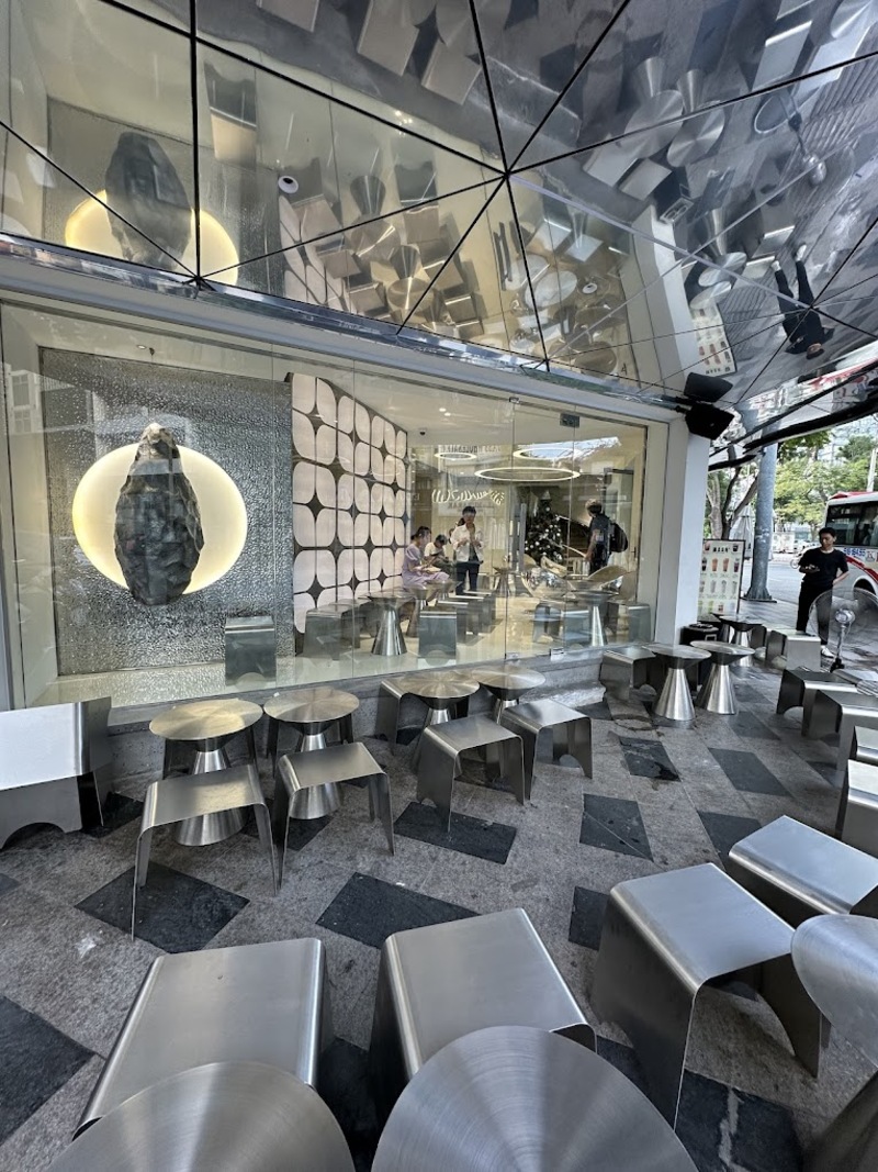 Qu&aacute;n c&agrave; ph&ecirc; hiện đại với b&agrave;n ghế kim loại, thiết kế nội thất độc đ&aacute;o v&agrave; bức tường k&iacute;nh lớn.