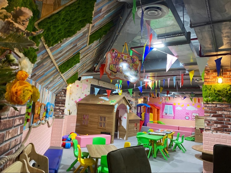 Khu vực chơi cho trẻ em trong nh&agrave; với b&agrave;n ghế, nh&agrave; gỗ nhỏ, đồ chơi v&agrave; trang tr&iacute; nhiều m&agrave;u sắc.