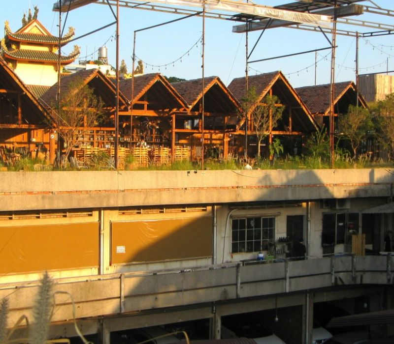 Khu vực nh&agrave; gỗ tr&ecirc;n tầng thượng, ph&iacute;a dưới l&agrave; cấu tr&uacute;c b&ecirc; t&ocirc;ng với cửa sổ v&agrave; cửa k&eacute;o, c&oacute; c&acirc;y xanh xung quanh.