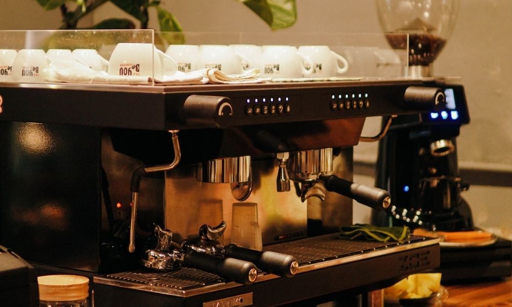 Khám Phá Top Quán Cafe Hấp Dẫn Trên Đường Nguyễn Chí Thanh - Điểm Đến Thú Vị 21 Máy pha cà phê chuyên nghiệp với nhiều tách trắng được xếp trên đỉnh, đặt trong không gian quán cà phê.