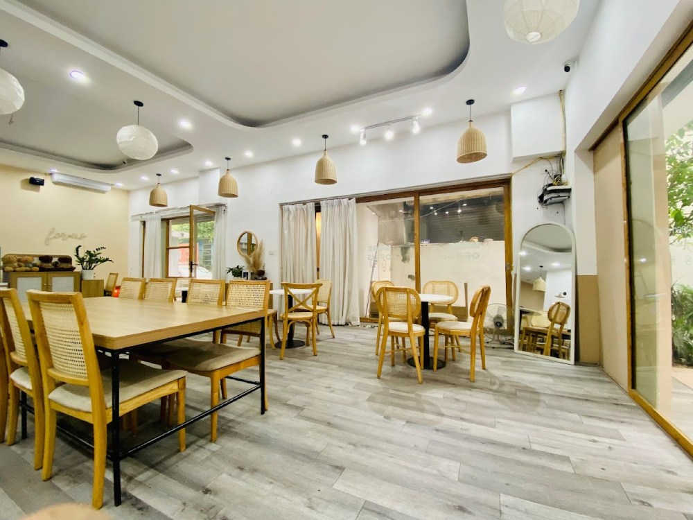 Phòng ăn hiện đại với bàn ghế gỗ, ánh sáng tự nhiên qua cửa kính lớn, trang trí đèn thả trần ấm cúng.