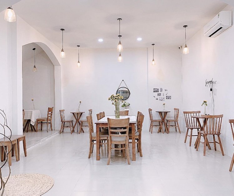 Kh&ocirc;ng gian qu&aacute;n c&agrave; ph&ecirc; với nội thất gỗ, trang tr&iacute; đơn giản v&agrave; &aacute;nh s&aacute;ng ấm &aacute;p từ c&aacute;c b&oacute;ng đ&egrave;n treo.