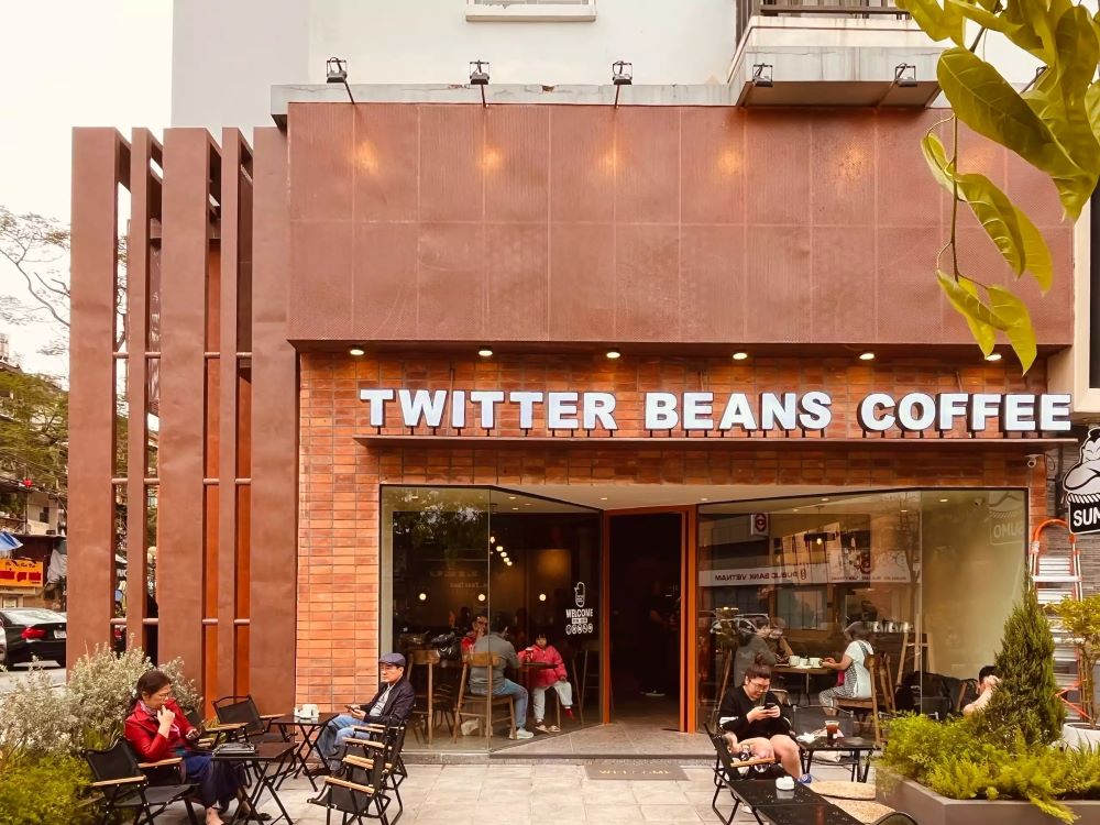 Ngoại thất quán cà phê Twitter Beans Coffee với khách ngồi bên ngoài, kiến trúc hiện đại và cây xanh xung quanh.