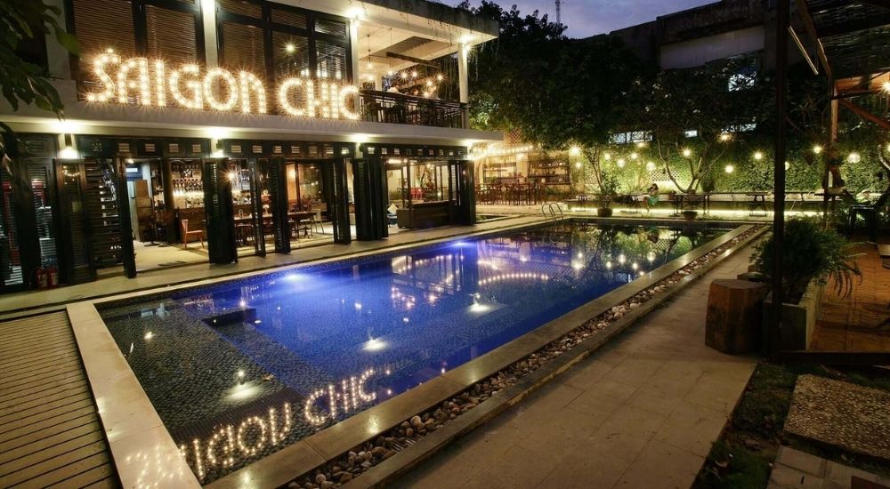 Khám Phá 10 Quán Cafe Gò Vấp Với Góc "Hidden Gem" Độc Đáo 12 Hồ bơi ngoài trời với ánh đèn lung linh, bên cạnh là một quán cà phê có không gian hiện đại và thoáng đãng.