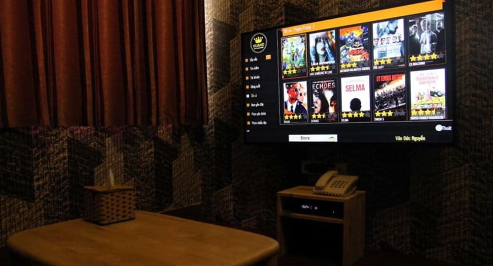 Top 9 Quán Cafe Phim Cầu Giấy Đáng Thử: Thưởng Thức Phim Hay, Cà Phê Ngon 15 Màn hình TV trên tường hiển thị danh sách phim với hình ảnh và đánh giá, bên dưới có điện thoại bàn.