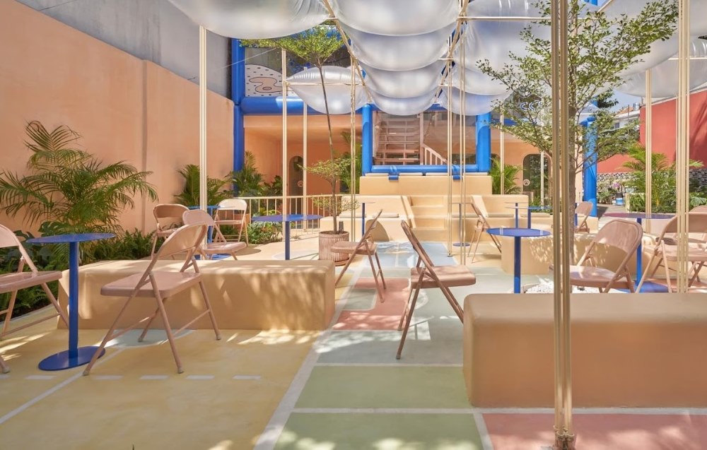 Kh&ocirc;ng gian ngo&agrave;i trời với b&agrave;n ghế gấp, c&acirc;y xanh v&agrave; m&aacute;i che trong suốt, thiết kế hiện đại v&agrave; gọn g&agrave;ng.