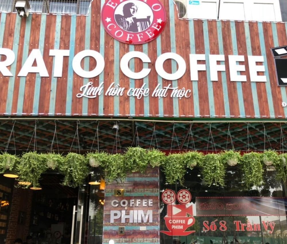 Top 9 Quán Cafe Phim Cầu Giấy Đáng Thử: Thưởng Thức Phim Hay, Cà Phê Ngon 4 Mặt tiền quán cà phê với biển hiệu lớn, trang trí cây xanh và cửa kính, có chữ "Coffee Phim" nổi bật.