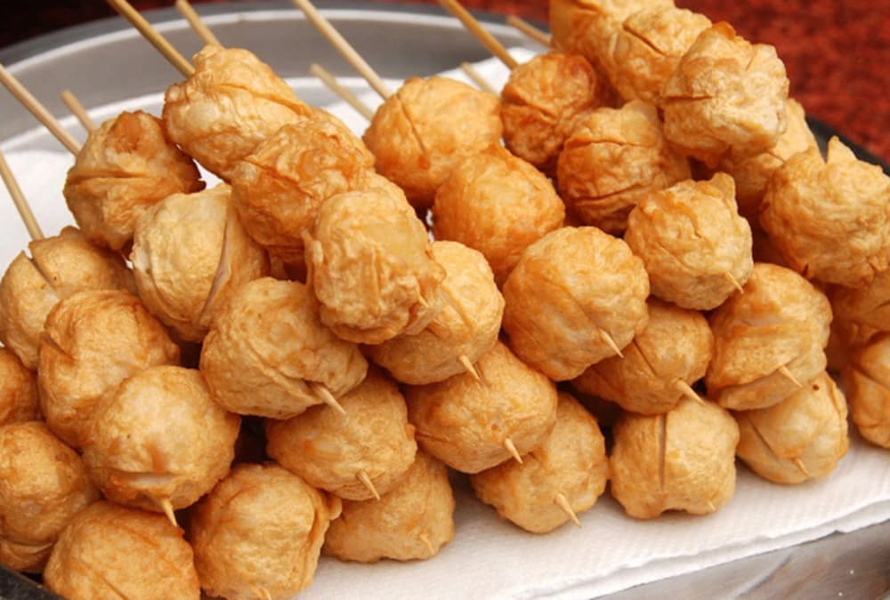 Khám Phá Cafe Bờ Kè Nóc Hầm Thủ Thiêm: Địa Điểm Thư Giãn và Ngắm Cảnh Tuyệt Vời 5 Nhiều xiên chả cá viên chiên vàng, được xếp chồng lên nhau trên khay, tạo nên một món ăn vặt hấp dẫn.