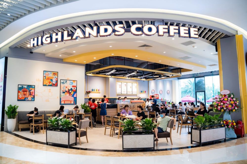 Khám Phá 10+ Quán Cafe Đẹp Nhất Long Biên: Thỏa Sức “Sống Ảo”, Thưởng Thức Đồ Uống Ngon 4 Quán cà phê với khách ngồi bên trong, nội thất hiện đại, có biển hiệu lớn và trang trí cây xanh.