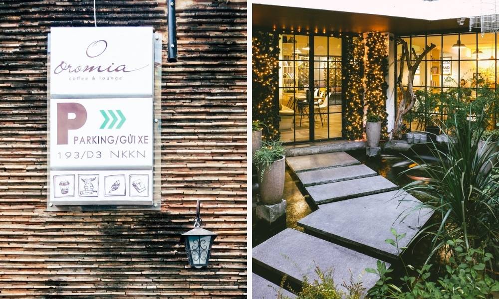 Khám Phá 15 Quán Cafe Yên Tĩnh ở Quận 1: Không Gian Thoải Mái, Thức Uống Tuyệt Hảo 3 Bảng hiệu và lối vào một quán cà phê với trang trí đèn và cây xanh xung quanh, tạo không gian ấm cúng.