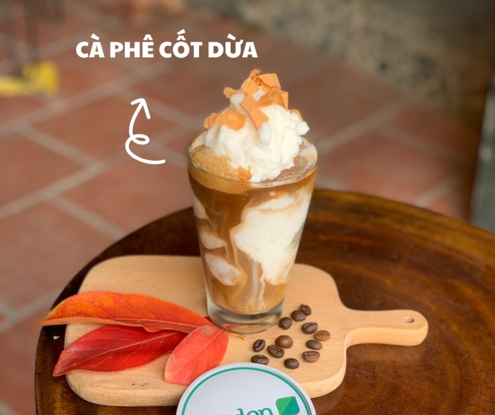 Khám Phá Garden Coffee Đội Cấn: Không Gian Yên Tĩnh Giữa Lòng Thủ Đô 8 Ly cà phê cốt dừa với lớp kem tươi, đặt trên bàn gỗ, bên cạnh là lá đỏ và hạt cà phê trang trí.