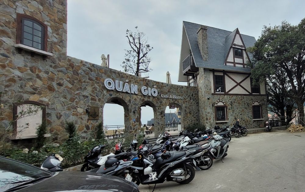 Khám Phá Quán Gió Tam Đảo: Trải Nghiệm Cafe Trên Mây Với View Tuyệt Đẹp 5 Quán cafe với kiến trúc đá cổ điển, nhiều xe máy đậu phía trước.