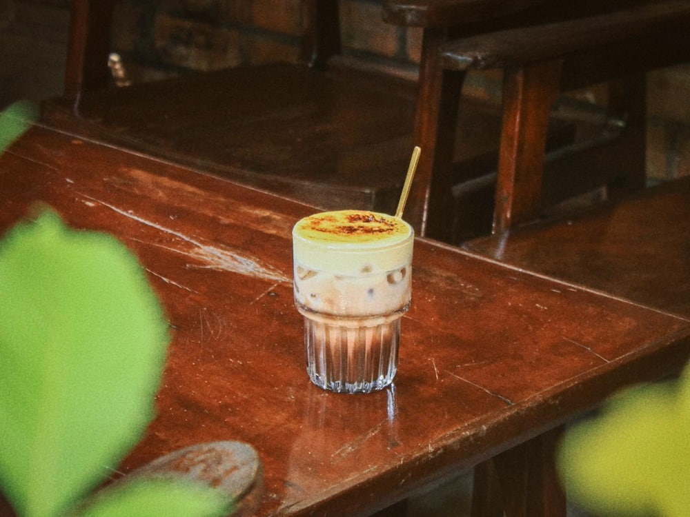 Khám Phá Cú Trên Cây Coffee: Không Gian Đà Lạt Giữa Lòng Sài Gòn 7 Ly cà phê trứng trên bàn gỗ nâu, có một chiếc ghế gỗ phía sau.