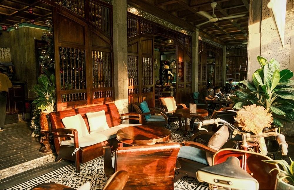12 Quán Cafe Sài Gòn Xưa Hấp Dẫn Nhất định Phải Thử 13 Quán cà phê với nội thất gỗ, chỗ ngồi thoải mái, cây xanh trang trí và ánh sáng tự nhiên chiếu vào.