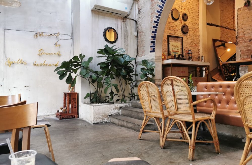Khám Phá 8+ Quán Cafe Đêm Sài Gòn Đẹp Lung Linh Bạn Không Thể Bỏ Lỡ 13 Quán cà phê với bàn ghế gỗ, cây xanh trang trí, tường gạch thô và chữ trang trí trên tường trắng.