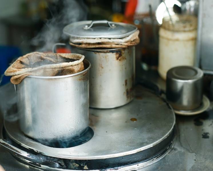 Hai nồi kim loại tr&ecirc;n bếp, một nồi c&oacute; t&uacute;i lọc vải, hơi nước bốc l&ecirc;n, xung quanh c&oacute; đồ d&ugrave;ng nh&agrave; bếp.