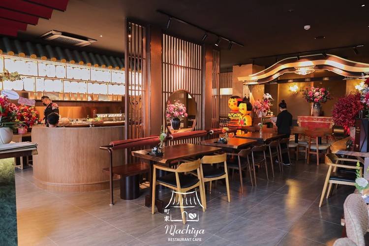 Nhà hàng Nhật Bản với nội thất ấm cúng, đèn lồng và hoa anh đào trang trí, khách đang thưởng thức món ăn.