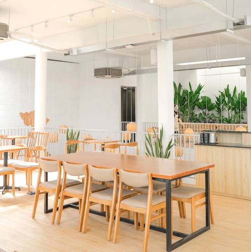 Qu&aacute;n c&agrave; ph&ecirc; hiện đại với b&agrave;n ghế gỗ, &aacute;nh s&aacute;ng tự nhi&ecirc;n v&agrave; c&acirc;y xanh trang tr&iacute;.