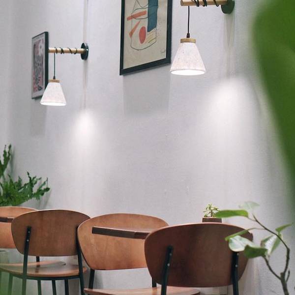 Qu&aacute;n c&agrave; ph&ecirc; phong c&aacute;ch tối giản với b&agrave;n ghế gỗ, đ&egrave;n treo tường v&agrave; tranh nghệ thuật tr&ecirc;n tường.