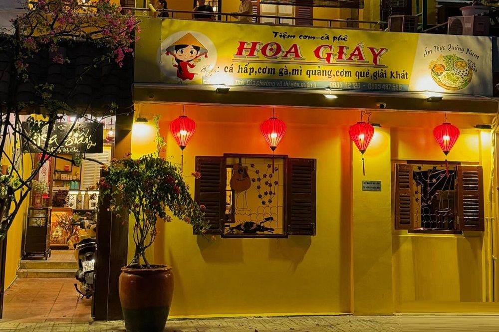 12 Quán Cafe Sài Gòn Xưa Hấp Dẫn Nhất định Phải Thử 14 Mặt tiền tiệm ăn và cà phê với đèn lồng đỏ treo, vách tường vàng và cây cảnh trước cửa.