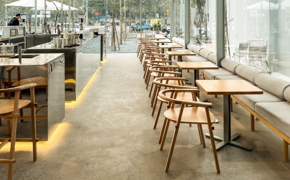 Qu&aacute;n c&agrave; ph&ecirc; hiện đại với b&agrave;n ghế gỗ, &aacute;nh s&aacute;ng dịu, kh&ocirc;ng gian tho&aacute;ng đ&atilde;ng nh&igrave;n ra cửa k&iacute;nh lớn.