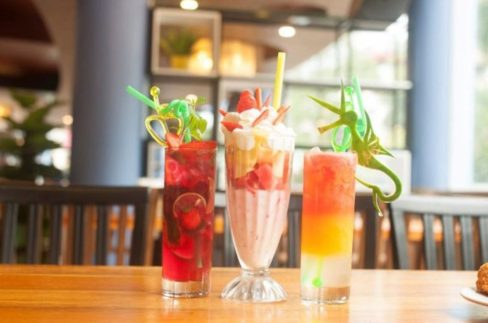 Khám Phá Du Miên Garden Cafe: Địa Điểm Độc Đáo Ngắm Sài Gòn Từ Trên Cao 7 Ba ly đồ uống đa dạng màu sắc trên bàn gỗ trong không gian quán cà phê sáng sủa.